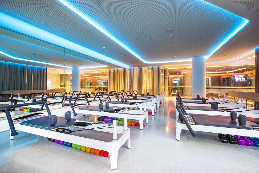 Inside the Joyful Pilates studio with rows of reformers and rainbow weights